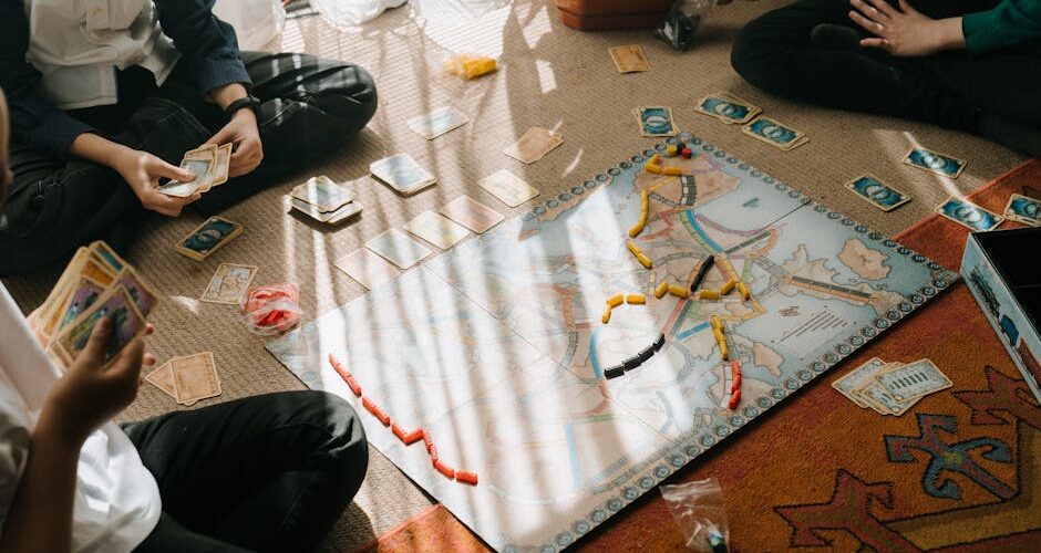 Kids enjoy a tabletop board game with map-based gameplay, cards, and tokens indoors.